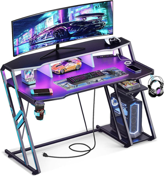 Gaming Desk with Power Outlet & LED Lights, Computer Desk 48 Inch with PC Storage Shelf, Gaming Table with Carbon Fiber Texture, Gamer Desk, Gift for Boys Men, Black