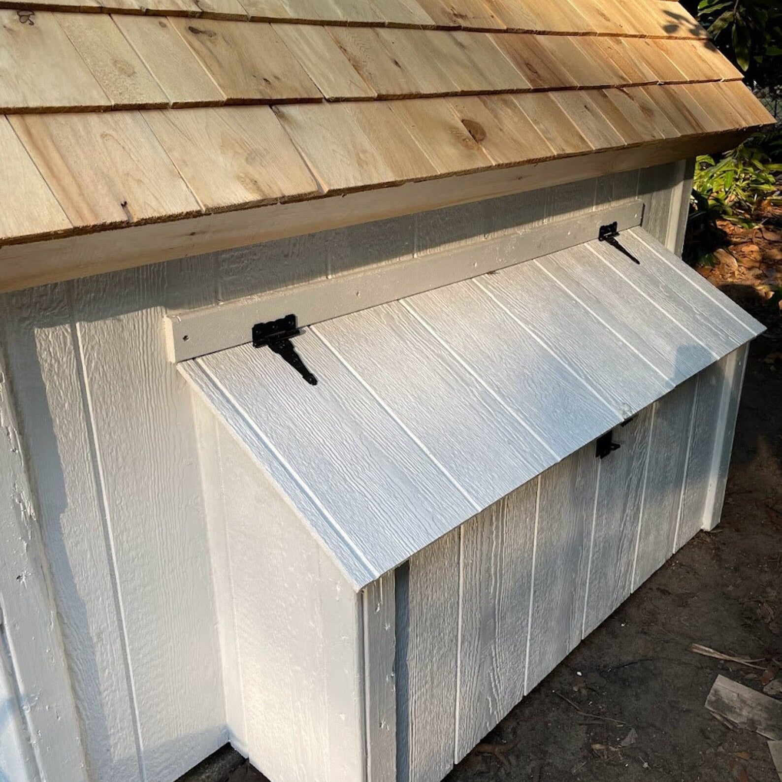 Small wooden shed with a slanted roof and metal door.