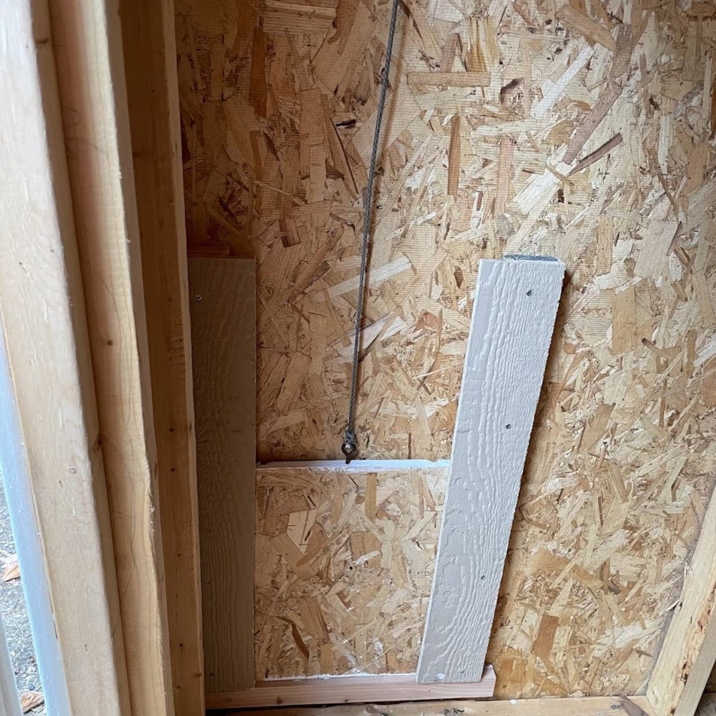 Wooden wall paneling with a piece of wood leaning against it in a construction setting.